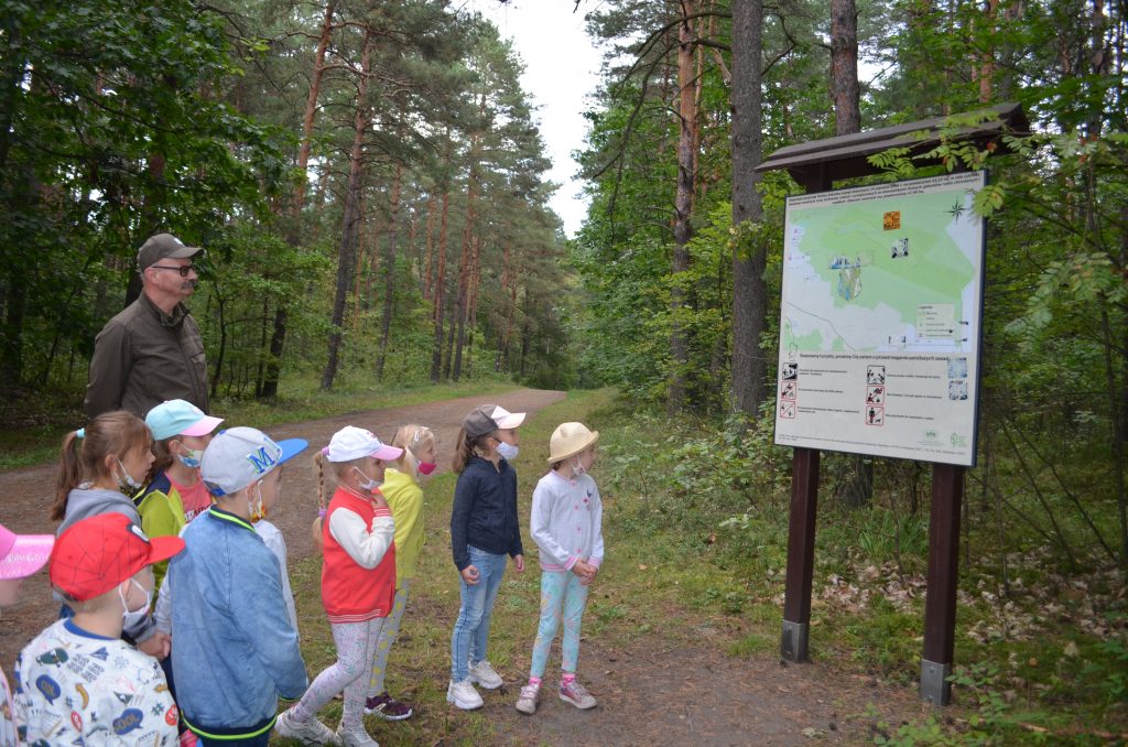 Dzieci z leśniczym patrzą na mapę rezerwatu przyrody Żabnik.