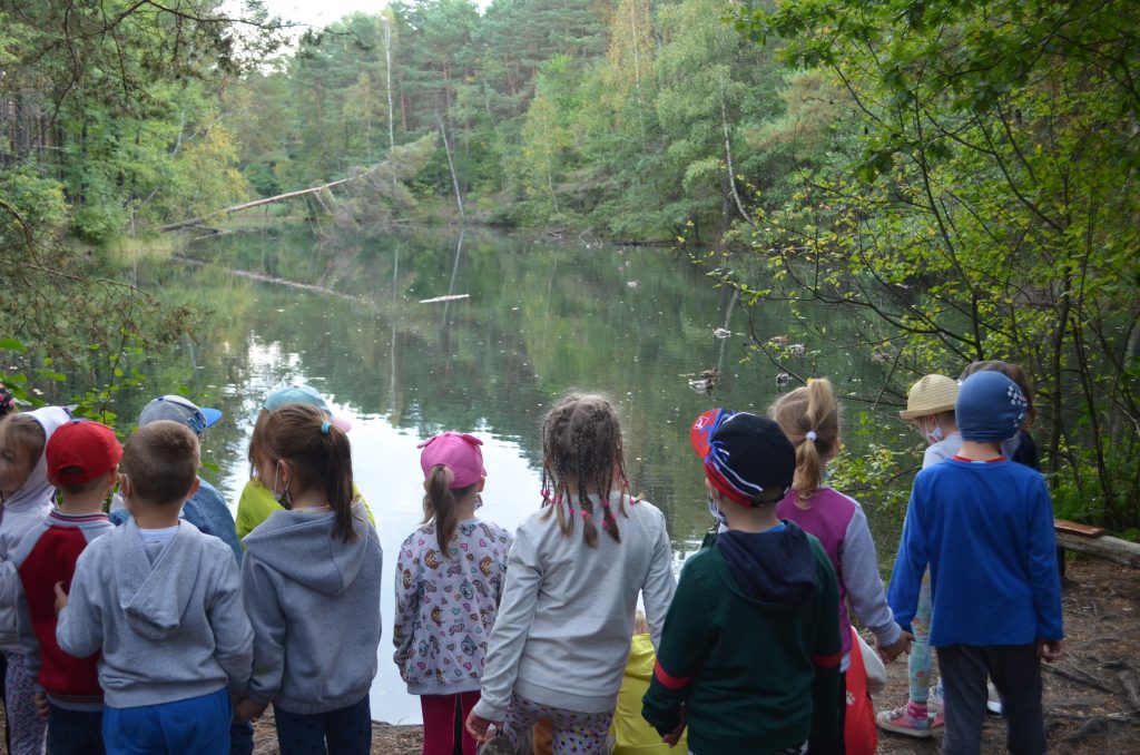 Dzieci obserwują kaczki pływające w zakolu potoku Żabnik.