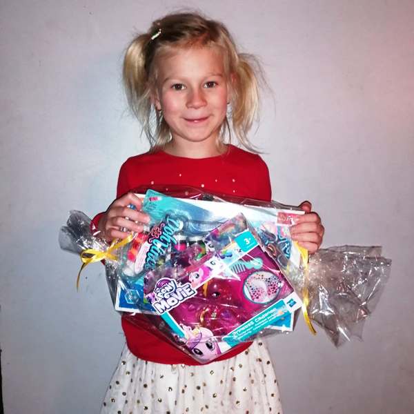 Na zdjęciu dziewczynka trzyma nagrodę, którą otrzymała w konkursie.