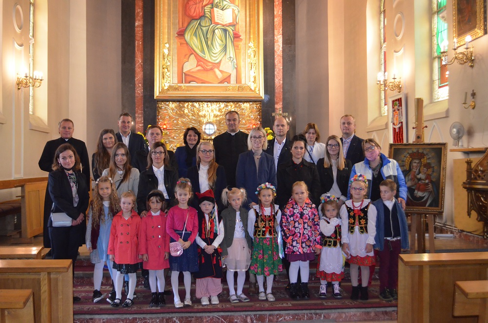 Zdjęcie przedstawia dzieci, rodziców, księży, dyrektora i pedagoga na tle ołtarza