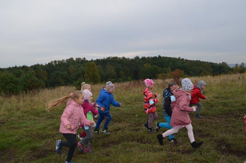 Dzieci biegną. Za nimi widać las.