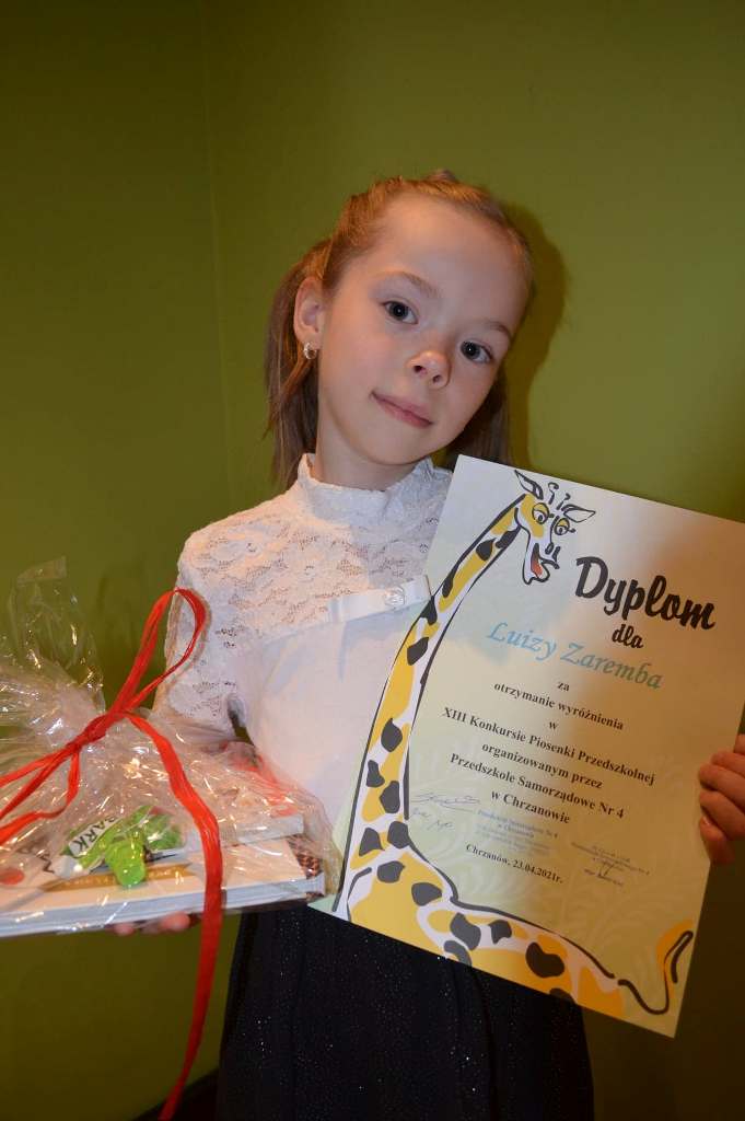 Dziewczynka trzyma w dłoniach dyplom oraz nagrodę.