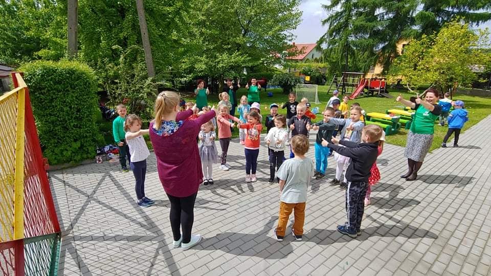 Na zdjęciu widać wesołe dzieci podczas obchodów Dnia Dziecka na przedszkolnym placu zabaw.