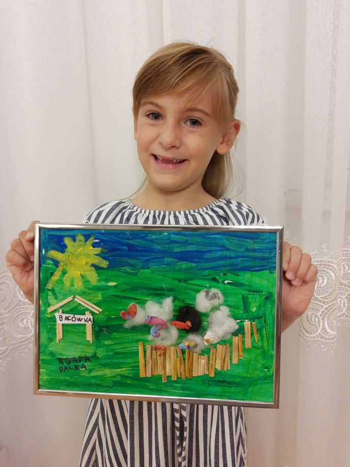 Dziewczynka ze swoją pracą plastyczną z konkursu "Wakacyjne podróże małe i duże".