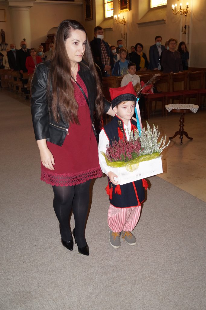 Chłopiec z mamą niesie dary ołtarza podczas mszy świętej.