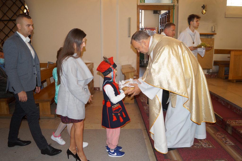 Chłopiec wręcza chleb księdzu proboszczowi podczas mszy świętej.