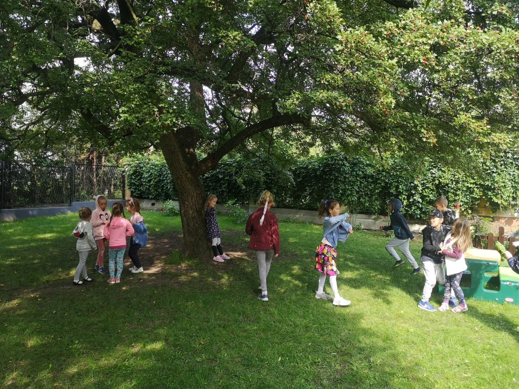 Dzieci w ogrodzie przedszkolnym podczas swobodnych zabaw na trawniku.