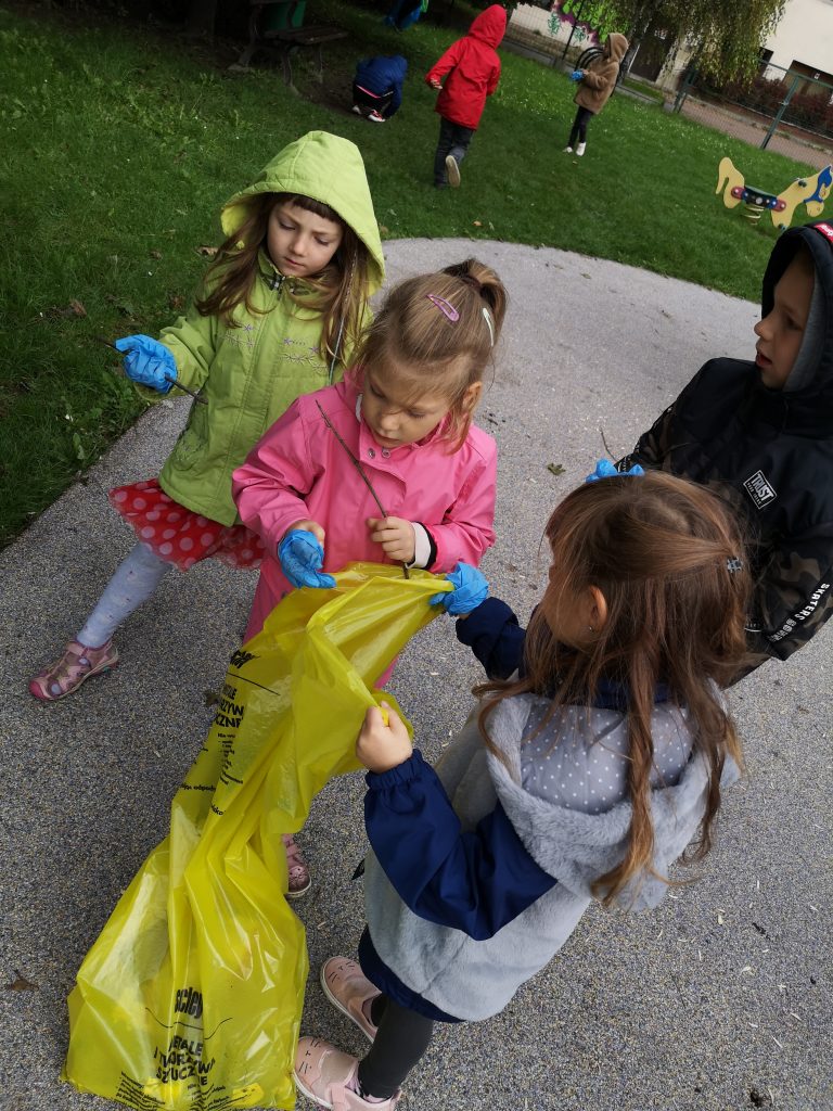 Dzieci wrzucają znalezione śmieci do odpowiedniego worka.
