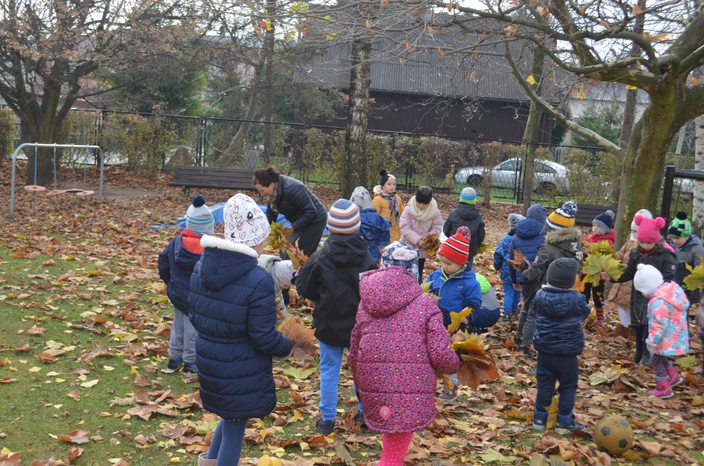 Zabawy z liśćmi jesiennymi na przedszkolnym placu zabaw.