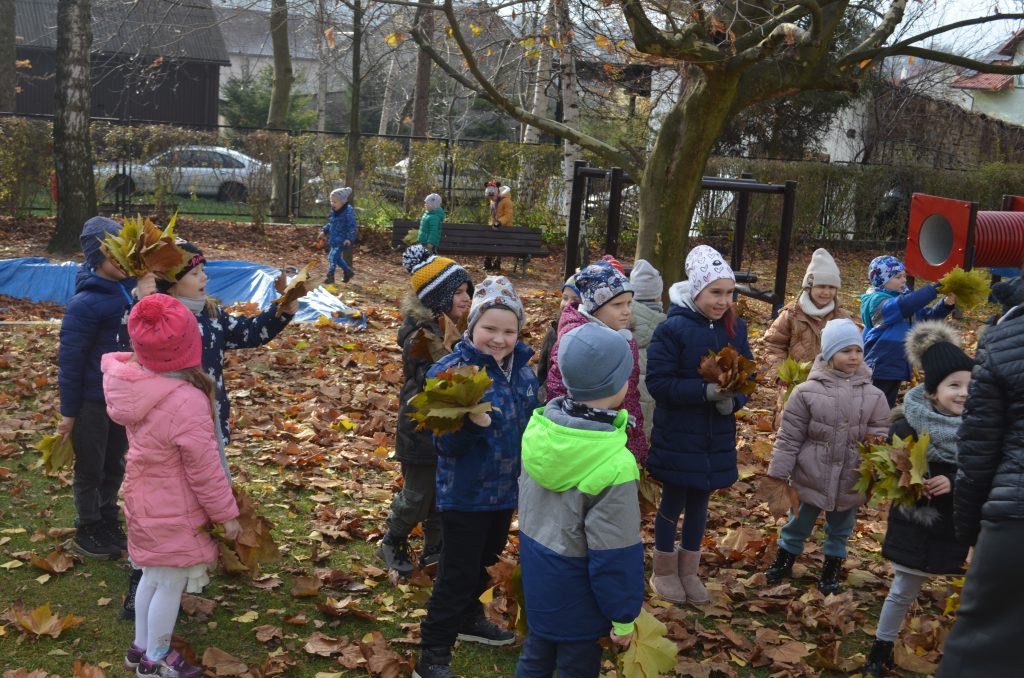 Dzieci podczas zabaw kolorowymi listkami na przedszkolnym placu zabaw.