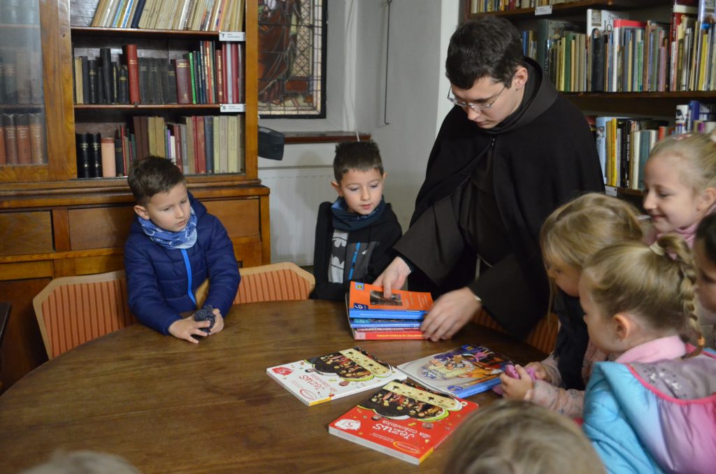 Ojciec Pio pokazuje dzieciom księgozbiory w bibliotece przyklasztornej.
