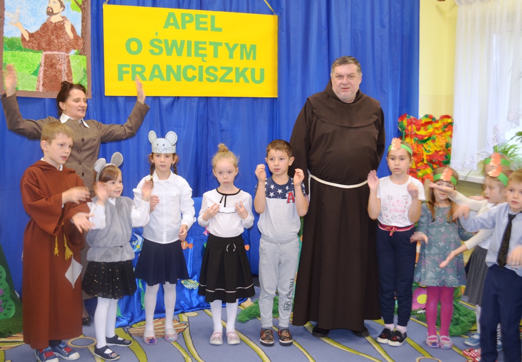 Zdjęcie przedstawia Ojca Lesława, Panią Dyrektor Jolantę Głowacz oraz dzieci śpiewające hymn przedszkola.