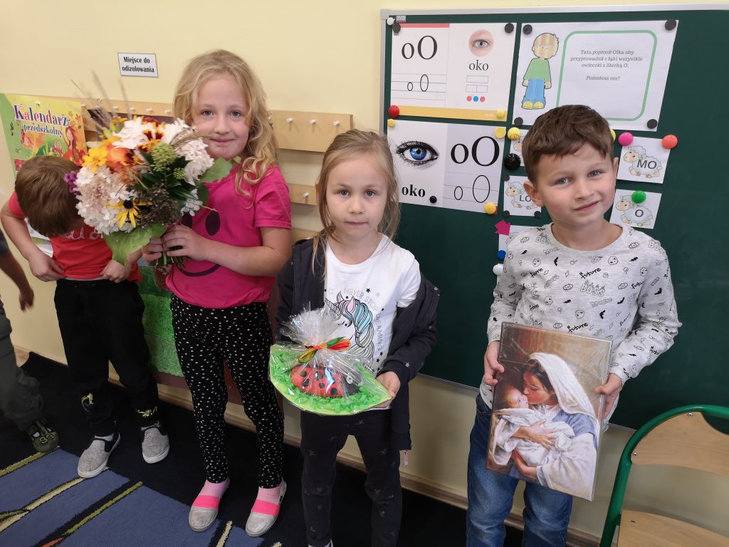 Dzieci trzymają prezenty przygotowane dla Księdza Rafała.