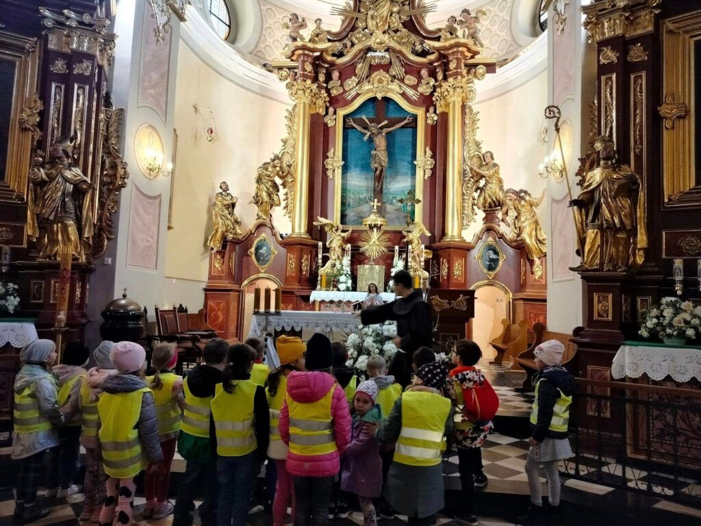 Dzieci znajdują się w kościele i oglądają ołtarz.