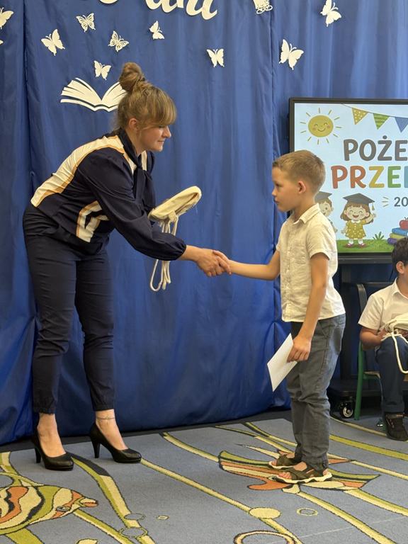 Pani Dyrektor wręcza chłopcu prezent.